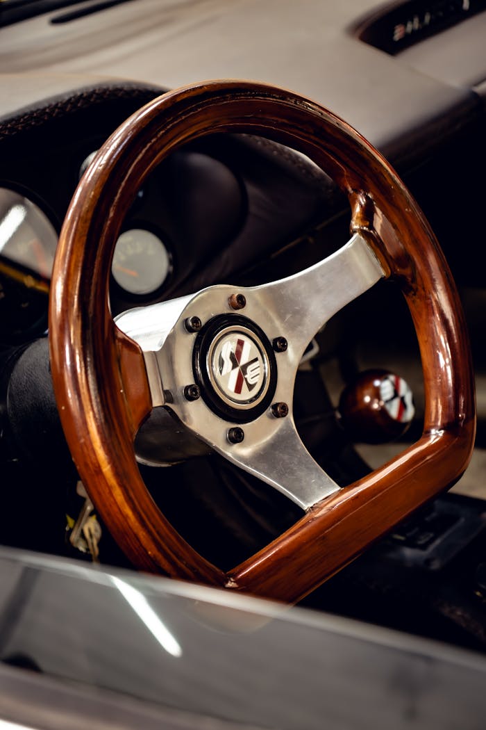 Close-up of a classic car's wooden steering wheel with a polished finish, offering a vintage feel.